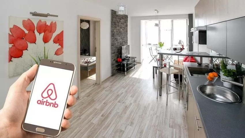 Image of a short term rental with a phone showing the Airbnb logo